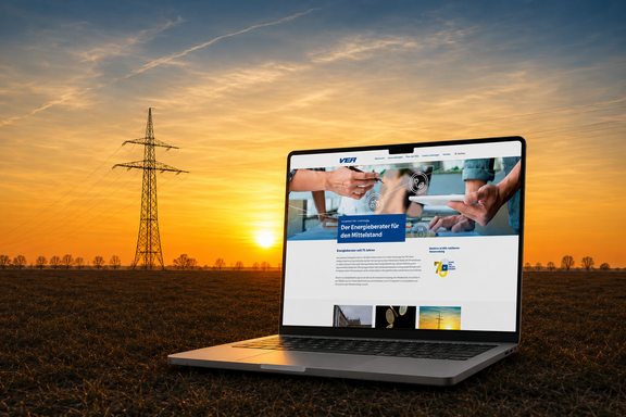 Ein Laptop zeigt die Startseite der neuen VEA-Website. Er steht auf einem Feld nahe einer Stromleitung im Sonnenuntergang.